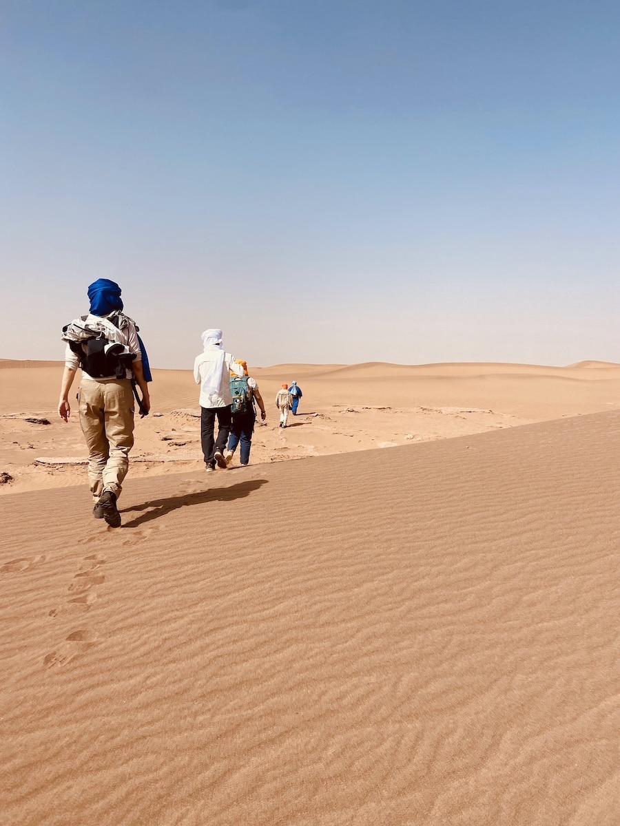 Groupe de voyageurs marchant dans les dunes du désert marocain lors d'une retraite spirituelle.