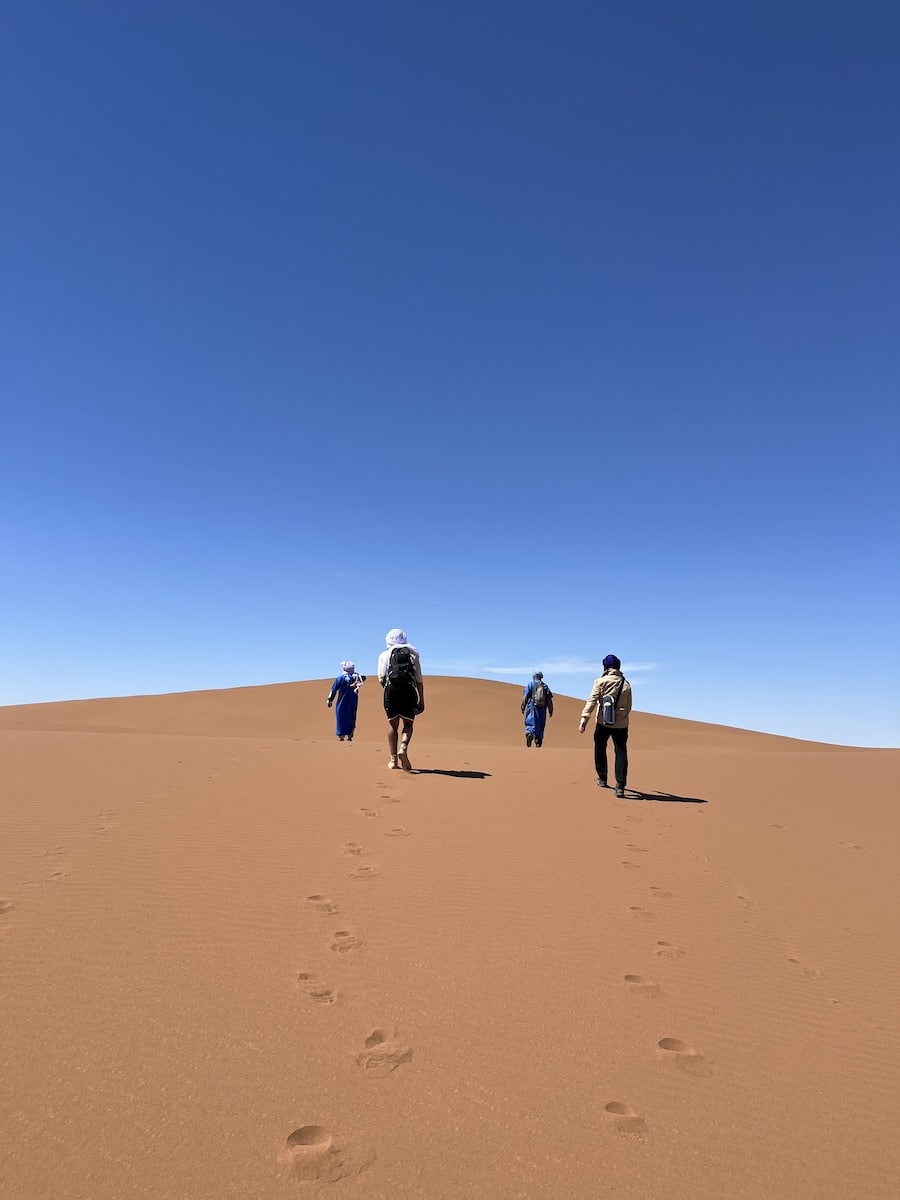 Groupe de voyageurs marchant dans le désert marocain pour une retraite de Nouvel An avec Maroc en Conscience