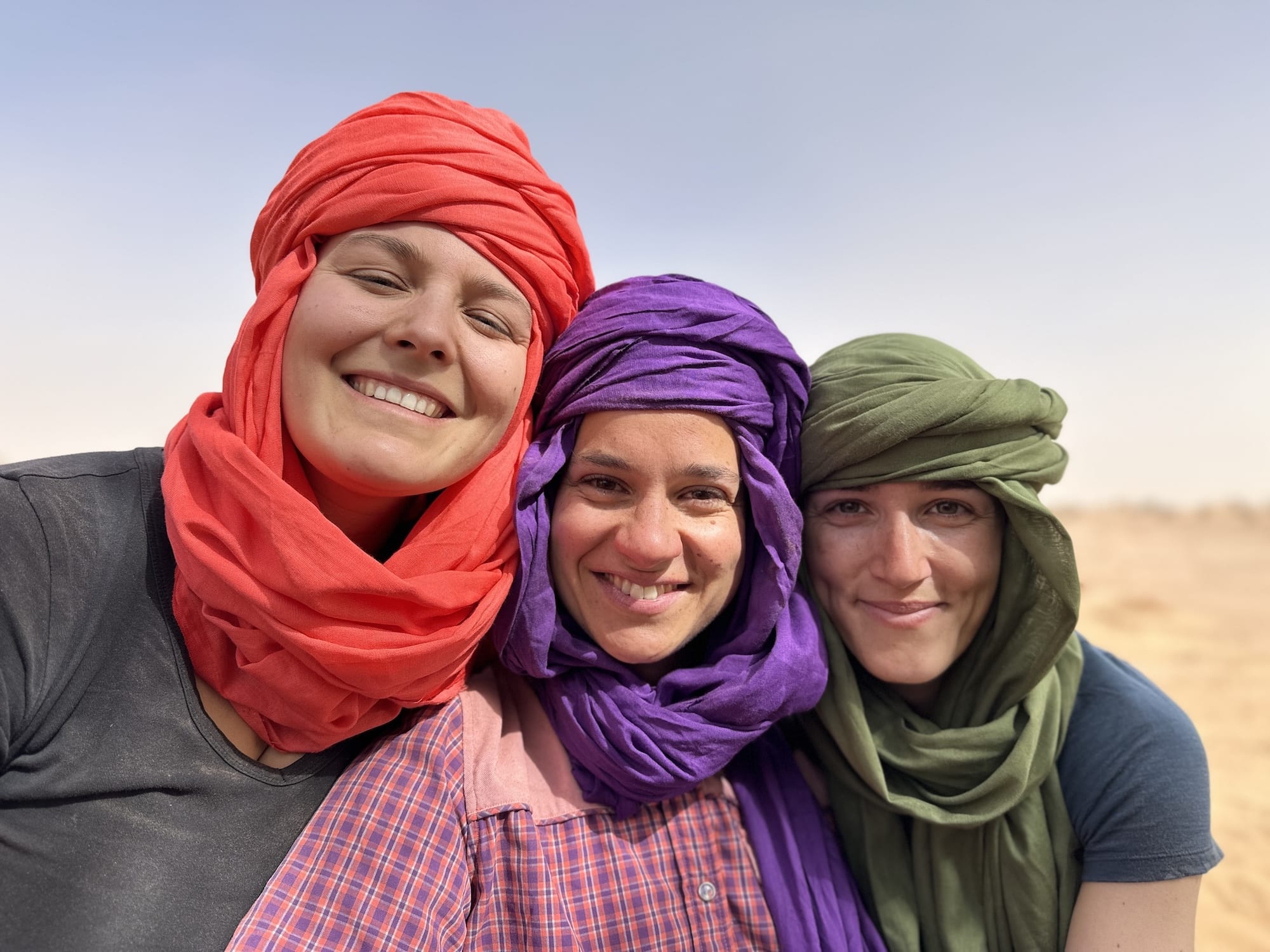 Participants souriants lors de la retraite de Nouvel An dans le désert marocain, partageant un moment convivial en petit groupe