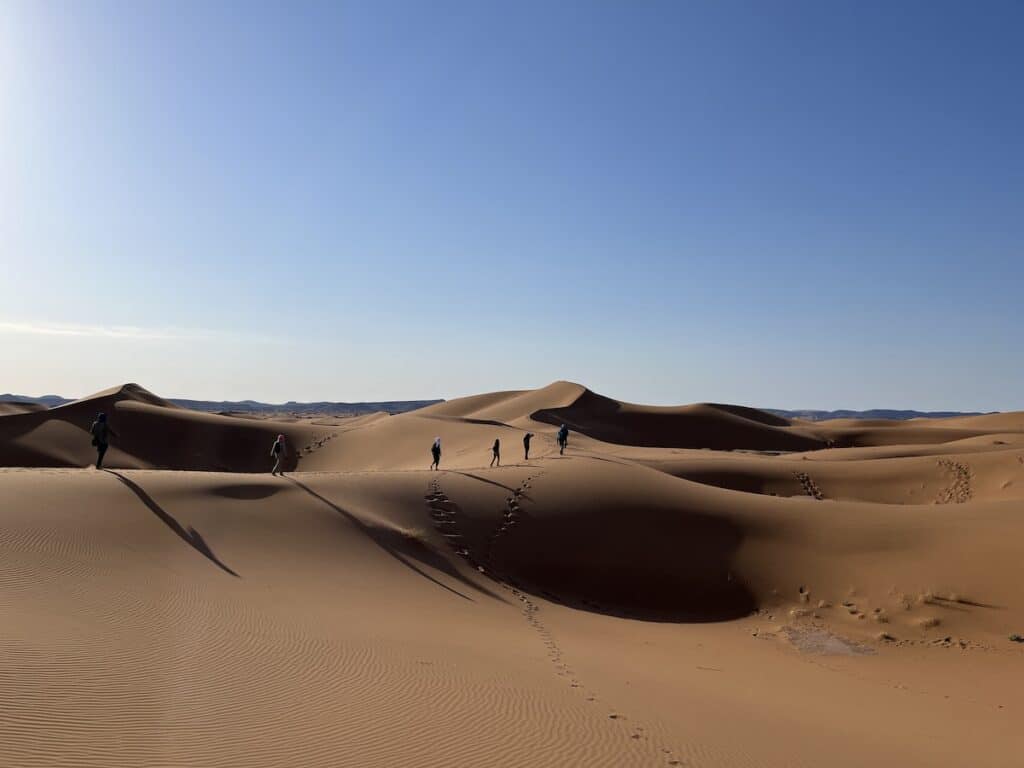 Voyageurs marchant sur les dunes marocaines lors de la retraite de Nouvel An organisée par Maroc en Conscience