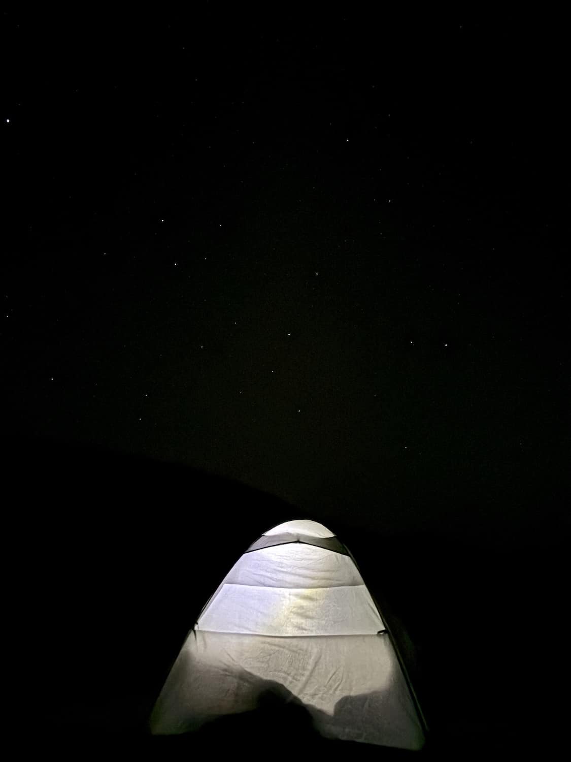 Tente éclairée sous le ciel étoilé dans le désert marocain, illustrant la sérénité de la retraite de Nouvel An avec Maroc en Conscience.