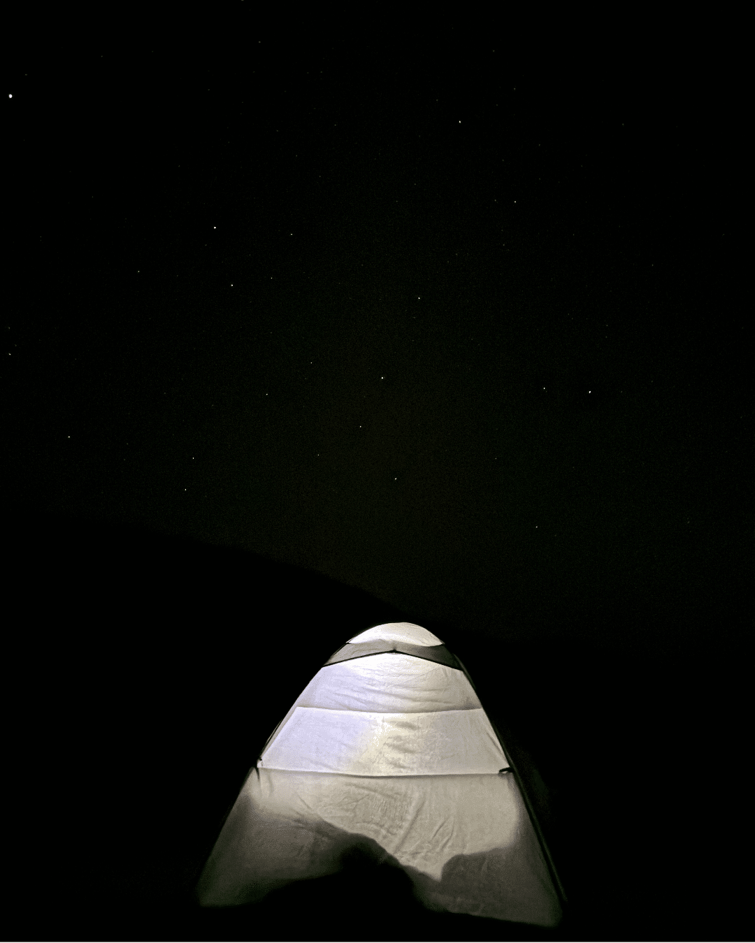 Tente éclairée sous le ciel étoilé du désert marocain.